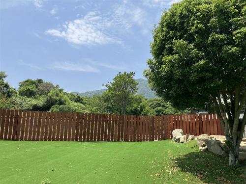 a wooden fence in a yard with a green lawn at いろどり荘 ドッグラン併設 露天風呂付き in Inokuchi