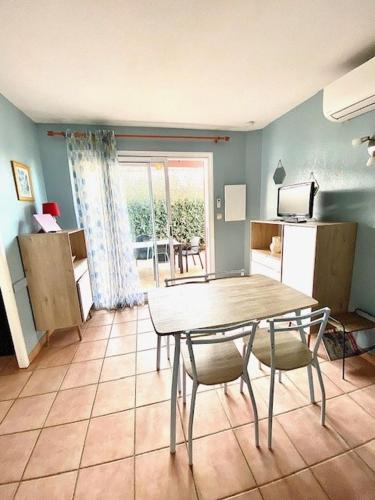 a kitchen with a table and chairs in a room at T2 cabine avec piscine collective, parking, climatisation, pour 4 personnes in Saintes-Maries-de-la-Mer