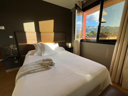 a bedroom with a white bed with a large window at Hotel Don Pablo in Villasana de Mena