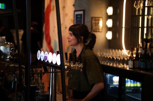 a woman standing behind a bar with bottles of wine at Drifter Christchurch in Christchurch