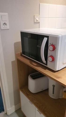 un four micro-ondes installé au-dessus d'une étagère dans l'établissement App 3 - T2 Calme et Lumineux Hyper-Centre 5min de la gare, à Évreux