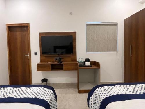 a hotel room with two beds and a television at The Crown Prince in Greater Noida