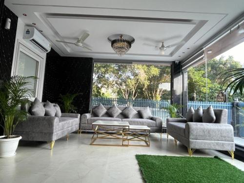 a living room with couches and a green rug at The Crown Prince in Greater Noida