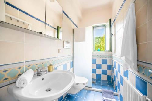 a blue and white bathroom with a sink and a toilet at Villa Fonesei in Kalami