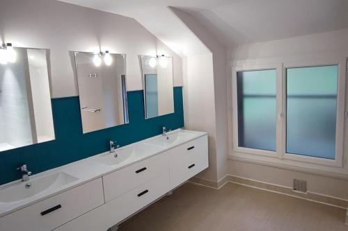 une salle de bain avec deux lavabos et deux miroirs dans l'établissement Grande maison familiale la bastide du puech, à Cransac