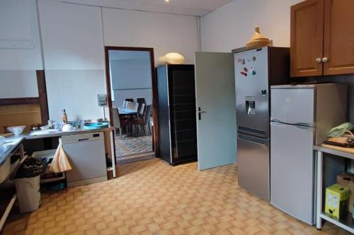 une cuisine avec des appareils en acier inoxydable et une table dans l'établissement Grande maison familiale la bastide du puech, à Cransac