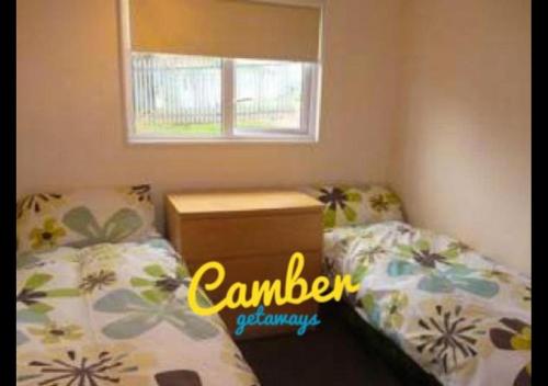 Un dormitorio pequeño con dos camas y una ventana. en K90 - Chalet - Parkdean Resorts, Camber Sands, en Camber