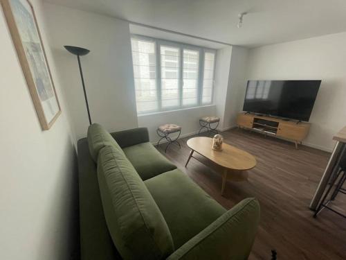 a living room with a green couch and a flat screen tv at Maison de ville- quartier calme in Vitré