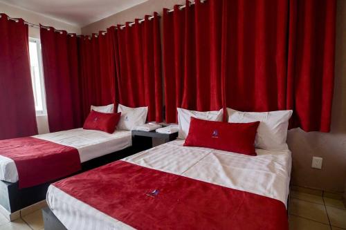 two beds in a hotel room with red curtains at Casa Del Agua Tepeji in Presa Requena
