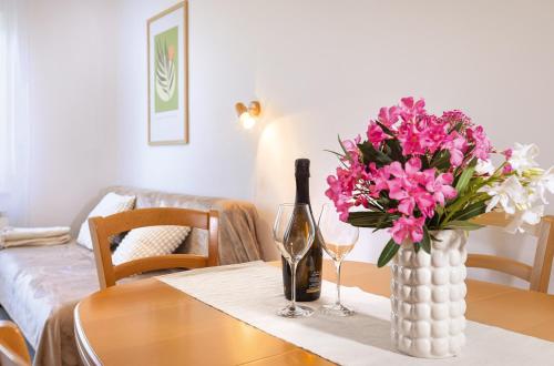 a table with a bottle of wine and a vase of pink flowers at House Olive Garden Strunjan in Strunjan
