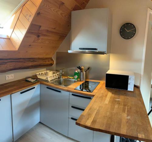 une cuisine avec des placards blancs et une horloge murale dans l'établissement Studio à louer à 1 h de Paris, à Montereau-faut-Yonne