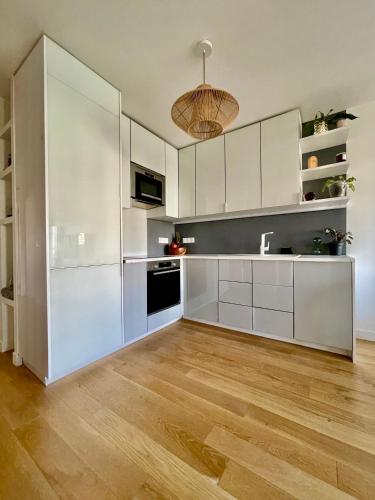 une cuisine avec des armoires blanches et un plancher en bois dans l'établissement Magnifique 3 pièces de 55m2 au calme avec balcon, à Paris