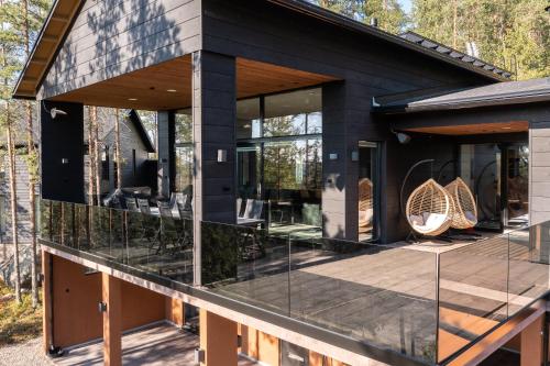 a black house with glass windows and chairs on a deck at Villa FeelGood Himos in Himos
