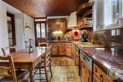 une grande cuisine avec des placards en bois et une table en bois dans l'établissement Les trois etangs, à Montreuil-sur-Ille