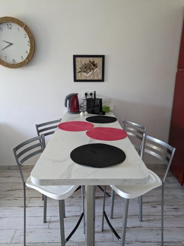 une table avec quatre chaises et une horloge sur le mur dans l'établissement Joli F2 Saint Endreol HAMEAU PALAYSON Var, à La Motte