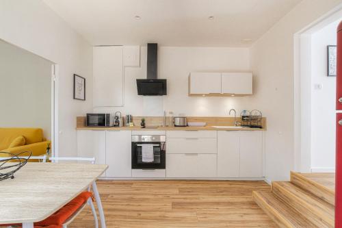 une cuisine avec des armoires blanches et un plancher en bois dans l'établissement Maison cosy avec terrasse à 15 minutes de Lyon et WIFI, à Rillieux-la-Pape