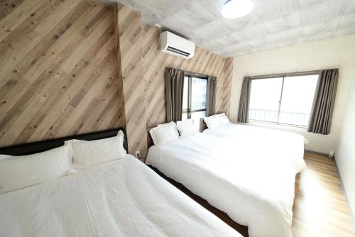 two beds in a room with wooden walls and windows at Shinjuku NY House 301 in Tokyo