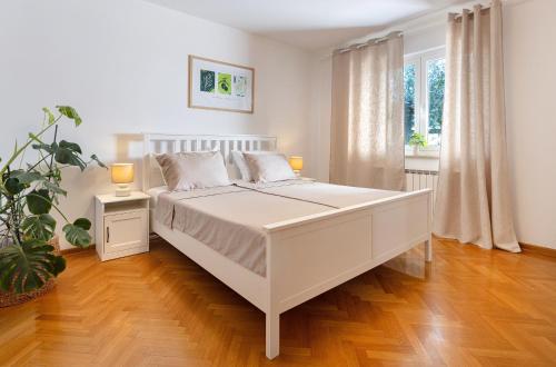 a white bedroom with a white bed and a plant at House Olive Garden Strunjan in Strunjan