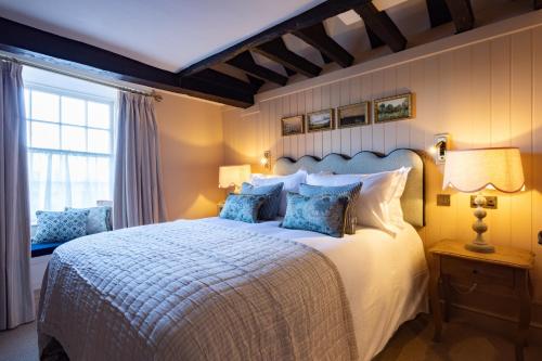 a bedroom with a large white bed with blue pillows at The White Hart - A Heartwood Inn in Lewes