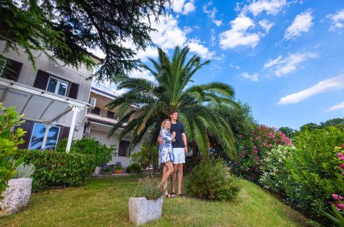 a man and woman standing in front of a palm tree at House Olive Garden Strunjan in Strunjan