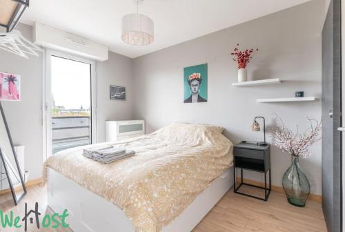 - une chambre blanche avec un lit et un vase de fleurs dans l'établissement Biscuiterie Terrasse parking centre ville, à Nantes