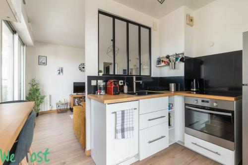 une cuisine avec des armoires blanches et des appareils noirs dans l'établissement Biscuiterie Terrasse parking centre ville, à Nantes