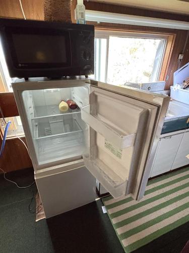 an empty refrigerator with its door open in a kitchen at 高野山ゲストハウス ラフテル Koyasan Guest House Laugh Tale in Hashimoto