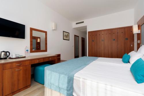 a bedroom with a bed and a desk and a television at Alua Helios Bay - All Inclusive in Obzor