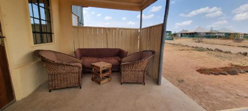 a porch with two wicker chairs and a couch at Amanya 2 Bedroom Self Catering Tent in Amboseli