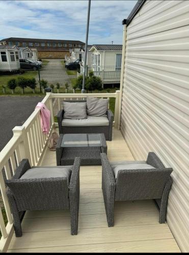 two wicker chairs and a table on a deck at SKEGNESS GOLDEN PALM HOLIDAY HOME Pg 52 in Skegness