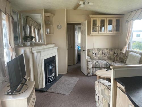 a living room with a fireplace and a couch at SKEGNESS GOLDEN PALM HOLIDAY HOME Pg 52 in Skegness
