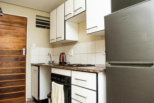 a kitchen with white cabinets and a stainless steel refrigerator at Mbizo Cozy Retreat 409 in Pretoria