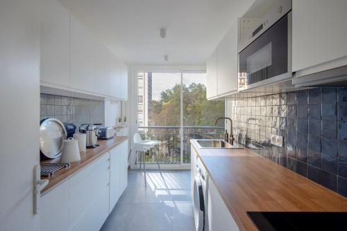 une cuisine avec des placards blancs et une grande fenêtre dans l'établissement Appartement Marseille VIEUX PORT, à Marseille
