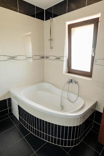 a bath tub in a bathroom with a window at Casa Korman in Giarmata