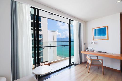 a room with a desk and a large window at TMS Hotel Da Nang Beach in Da Nang