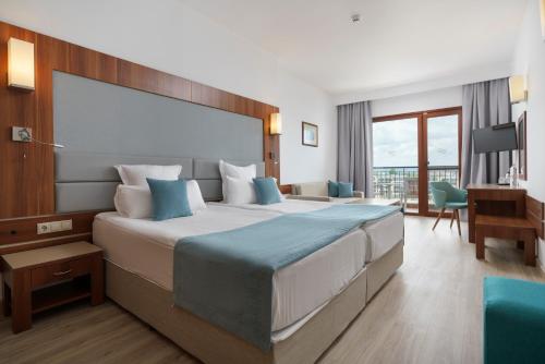 a hotel room with a large bed and a desk at Alua Helios Bay - All Inclusive in Obzor
