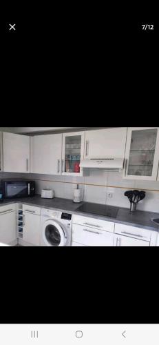 une cuisine avec des armoires blanches et une machine à laver dans l'établissement APT 2 chambres vue exceptionnelle, à Tiuccia