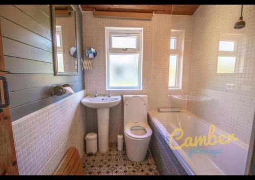 a bathroom with a sink and a toilet and a tub at Five Waterings - Puddock Farm Romney Marsh in Brookland