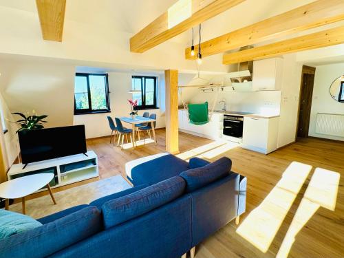 a living room with a blue couch and a kitchen at Stará Škola Mariánská in Albrechtice v Jizerských horách
