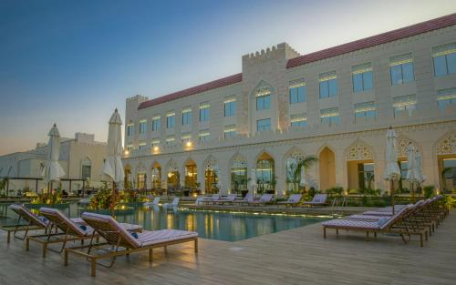a hotel with lounge chairs and a swimming pool at Golden Tulip Zanzibar Airport Hotel & Spa in Zanzibar City