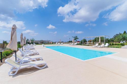a swimming pool with lounge chairs and umbrellas at Borgo Monachella in Ragusa