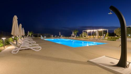 a swimming pool at night with chairs and umbrellas at Borgo Monachella in Ragusa