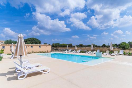 a pool with lounge chairs and an umbrella at Borgo Monachella in Ragusa