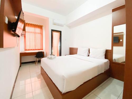 a bedroom with a white bed and a television at Homey Studio Cordova Edupartment Semarang Apartment By Travelio in Semarang