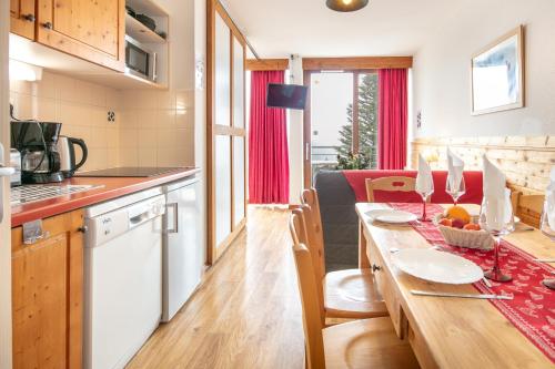 une cuisine et un salon avec une table en bois, une cuisine et une salle à manger dans l'établissement Hermine - apt 6p vue montagne, à Chamrousse
