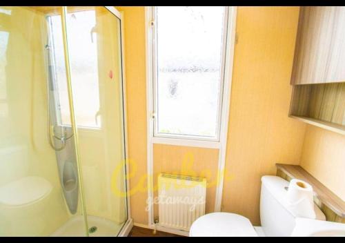 a bathroom with a shower and a toilet and a window at MP502 - Camber Sands Holiday Park - Sleeps 6 - Small Dog - Gated Decking - Amazing Marsh Views in Camber