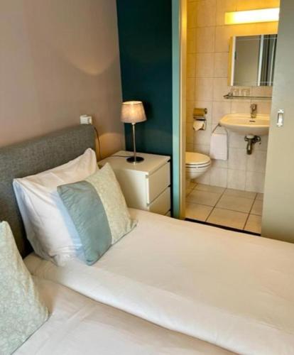 a bedroom with a bed and a bathroom at Herberg de la Ruïne in Valkenburg
