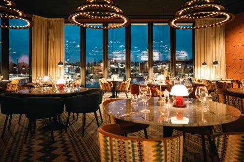 a restaurant with tables and chairs and large windows at Hotell Lappland in Lycksele