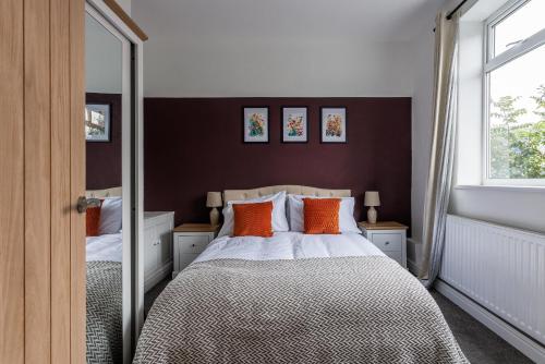 a bedroom with a bed with orange pillows and a mirror at Stylish 3-br Home In Gateshead Near Newcastle in Gateshead