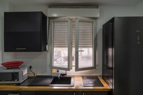 une cuisine avec un four micro-ondes et une fenêtre dans l'établissement Studio Cosy au Cœur de Paris 11e, à Paris